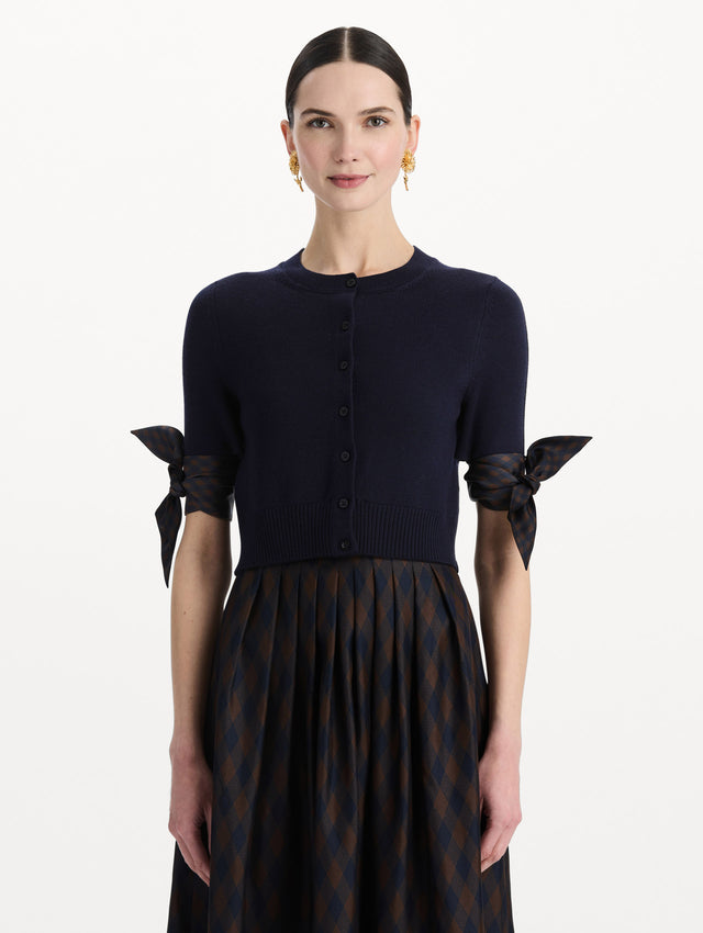The model is wearing the argyle tie-detailed cardigan in the color navy. Front view. 