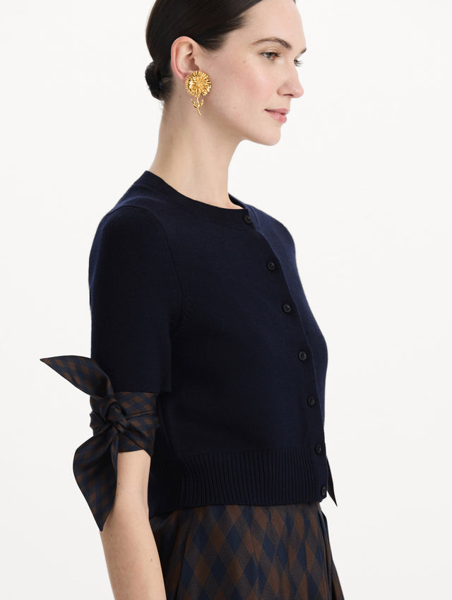 The model is wearing the argyle tie-detailed cardigan in the color navy. Zoom view. 