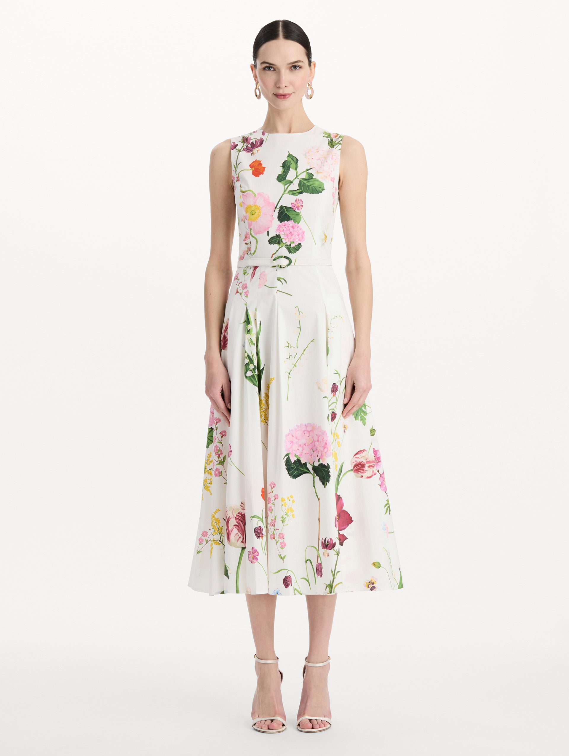 The model is wearing the mixed botanical cotton poplin sleeveless dress with an all-over floral print in white multi. Front view.