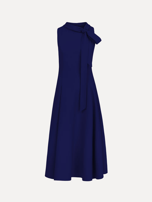 The model is wearing the Bow-Detailed Wool Dress with a sleeveless silhouette in the color navy.