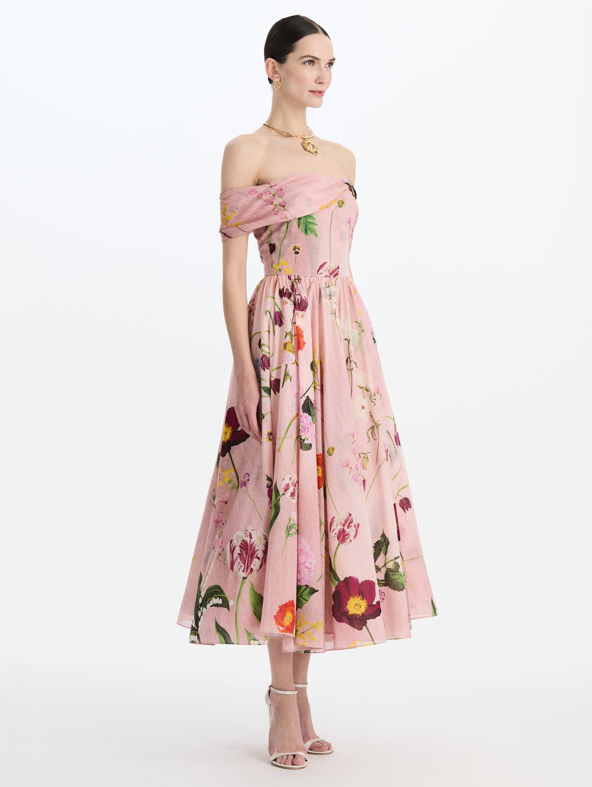 The model is wearing the mixed botanical off-shoulder dress in organic cotton with a floral print in a blush multi palette. Side view.