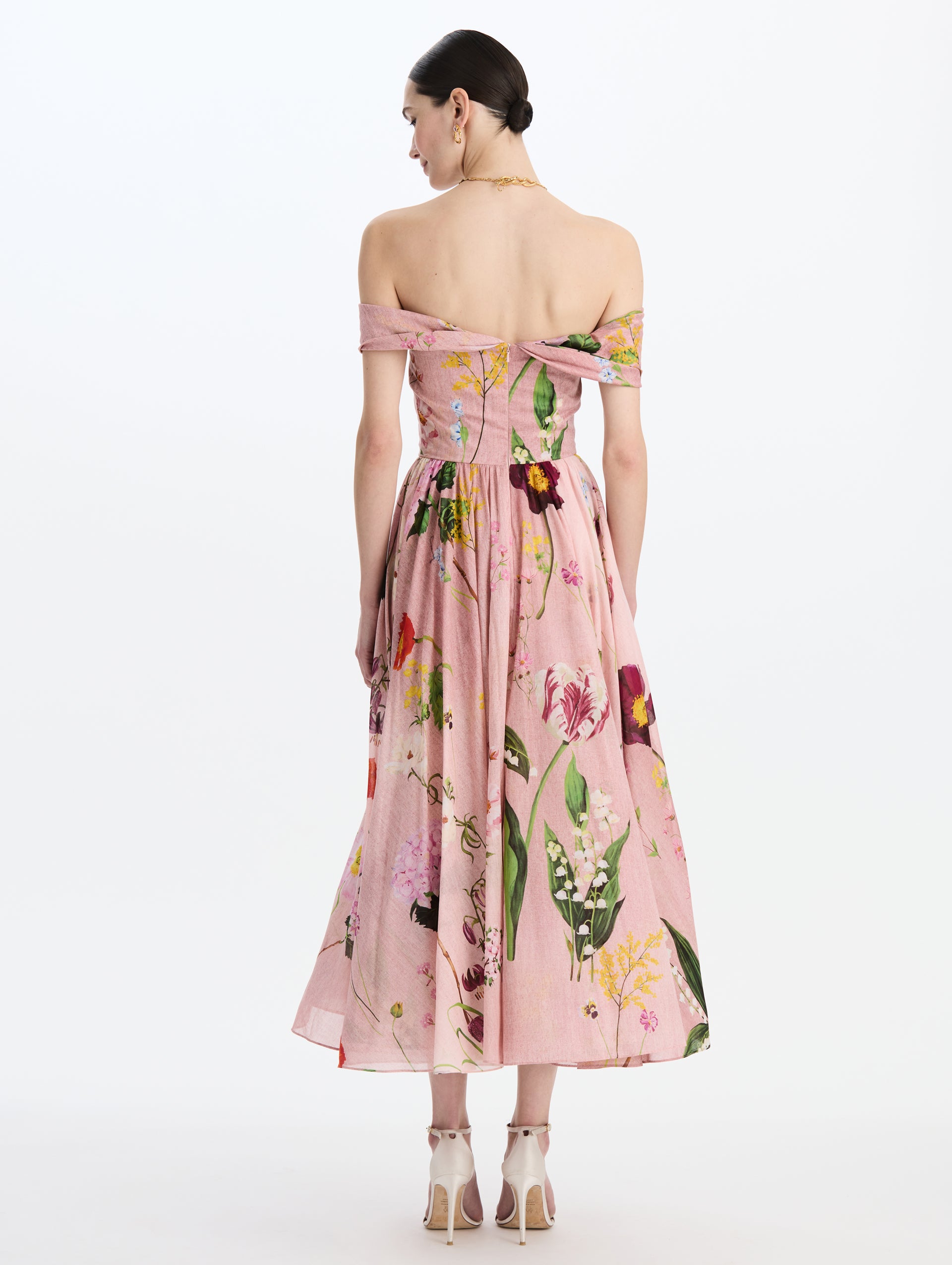 The model is wearing the mixed botanical off-shoulder dress in organic cotton with a floral print in a blush multi palette. Back view.