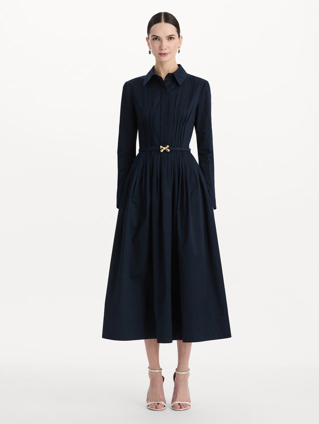 The model is wearing the bow belt cotton stretch twill dress with a collared neckline and long sleeves in the color navy. Front view. 