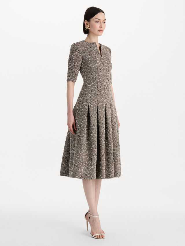 The model is wearing the Slub Wool Tweed Gauze Dress with midi sleeves in an ivory and brown palette. Side view. 