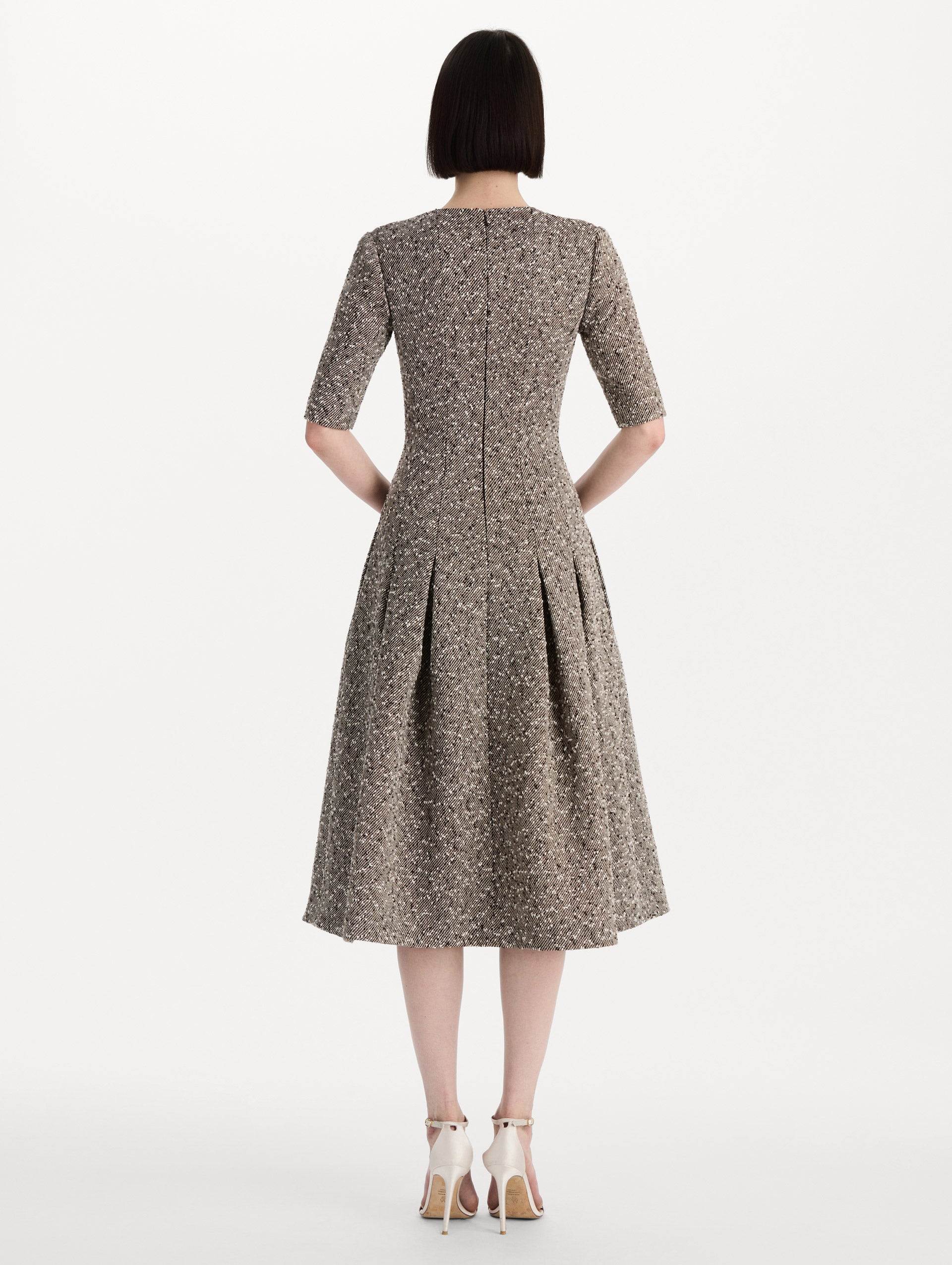 The model is wearing the Slub Wool Tweed Gauze Dress with midi sleeves in an ivory and brown palette. Back view. 