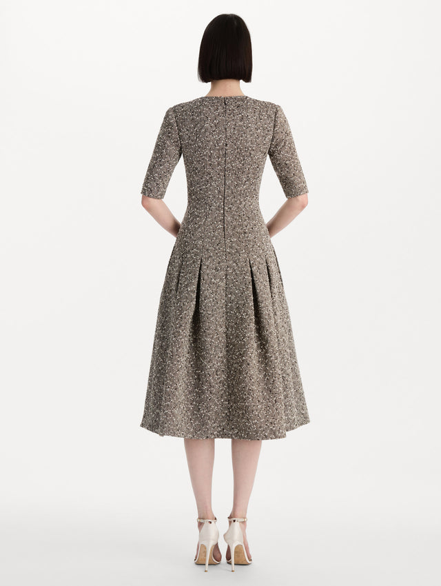 The model is wearing the Slub Wool Tweed Gauze Dress with midi sleeves in an ivory and brown palette. Back view. 