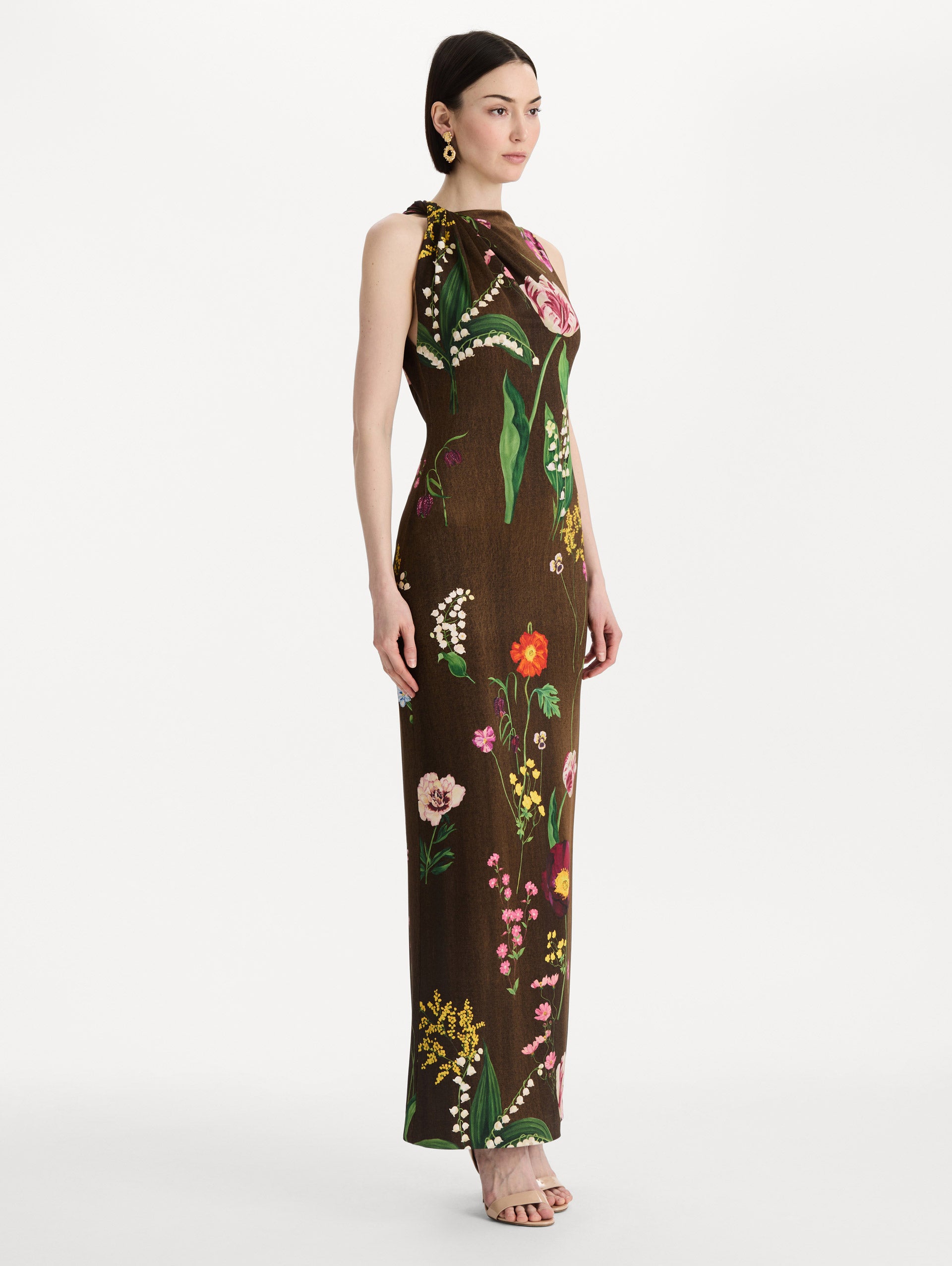 The model is wearing the mixed botanical Milano jersey dress with a sleeveless silhouette in a brown multi palette. Side view. 