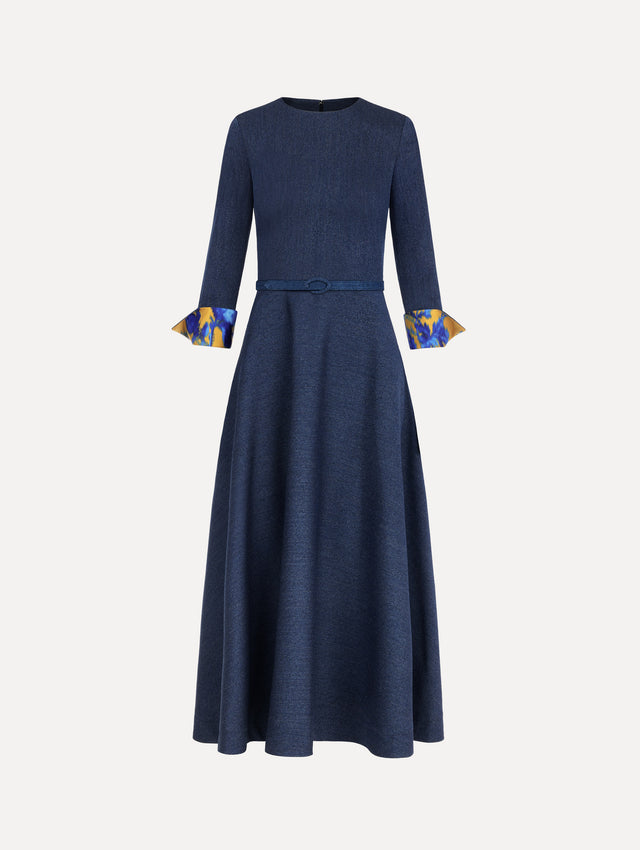 The model is wearing the peony cuff wool dress in the color indigo with peony-print cuffs and midi sleeves.