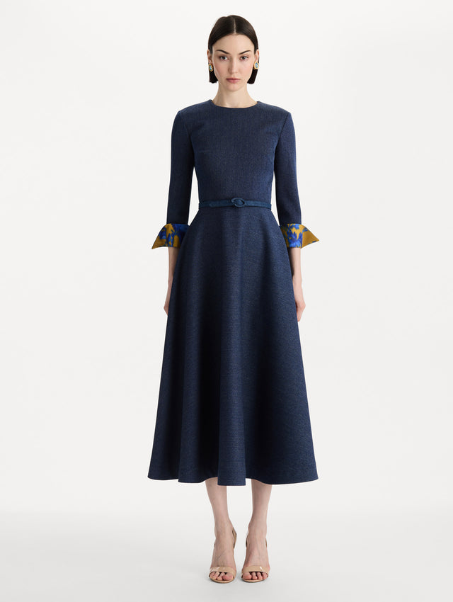 The model is wearing the peony cuff wool dress in the color indigo with peony-print cuffs and midi sleeves. Front view. 