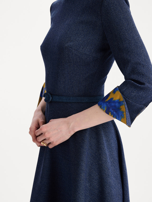 The model is wearing the peony cuff wool dress in the color indigo with peony-print cuffs and midi sleeves. Zoom view. 