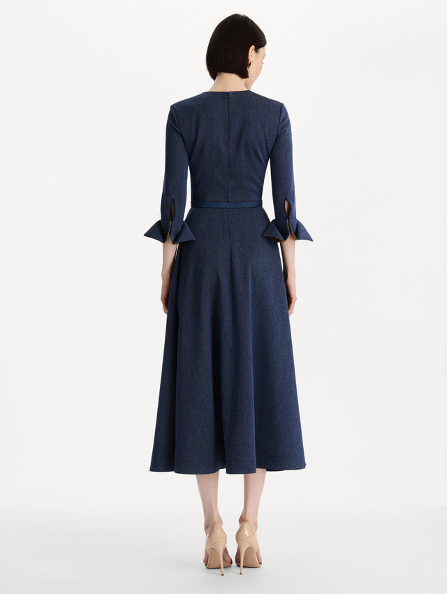 The model is wearing the peony cuff wool dress in the color indigo with peony-print cuffs and midi sleeves. Back view. 