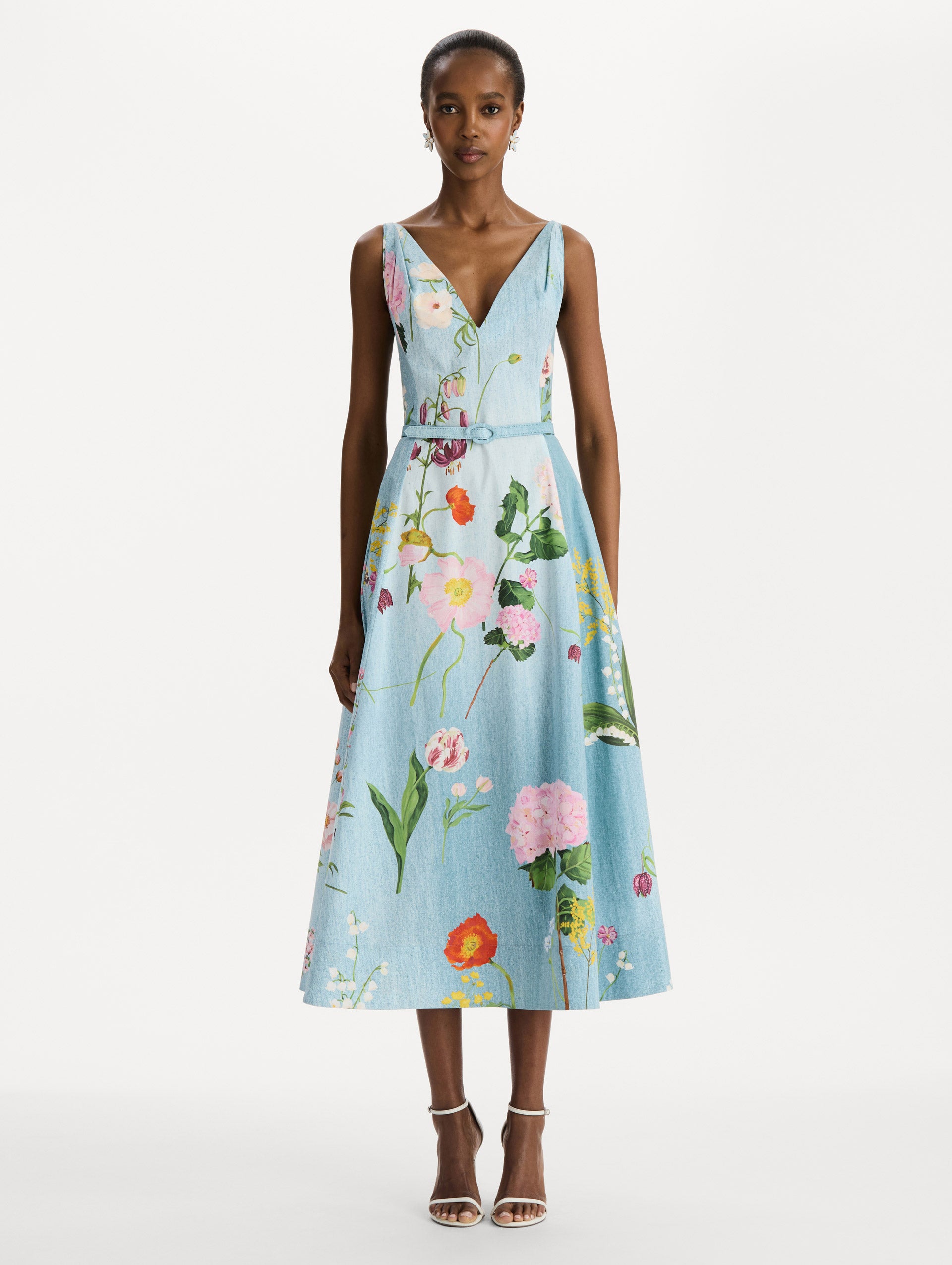 The model is wearing the mixed botanical cotton poplin dress with a sleeveless V-neck silhouette and an all-over floral print in blue multi.