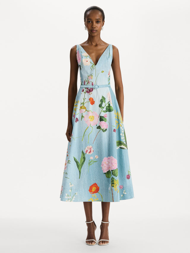 The model is wearing the mixed botanical cotton poplin dress with a sleeveless V-neck silhouette and an all-over floral print in blue multi.