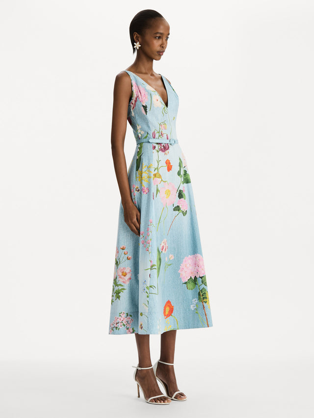 The model is wearing the mixed botanical cotton poplin dress with a sleeveless V-neck silhouette and an all-over floral print in blue multi. Side view. 