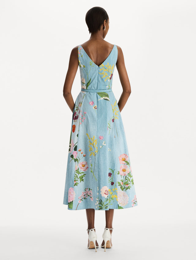 The model is wearing the mixed botanical cotton poplin dress with a sleeveless V-neck silhouette and an all-over floral print in blue multi.