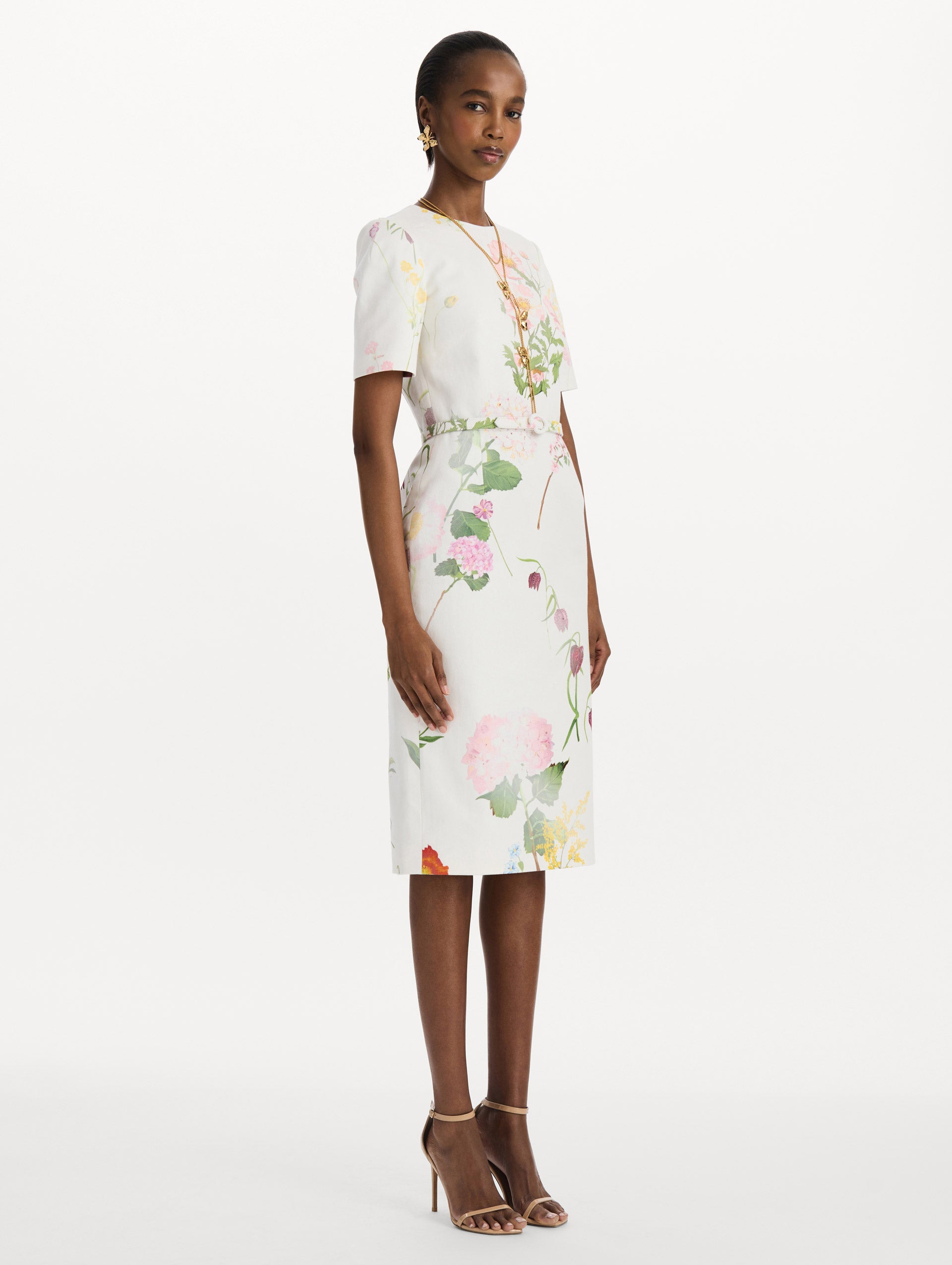 The model is wearing the faded mixed botanical denim dress with midi sleeves and a washed floral print in white multi. Side view.