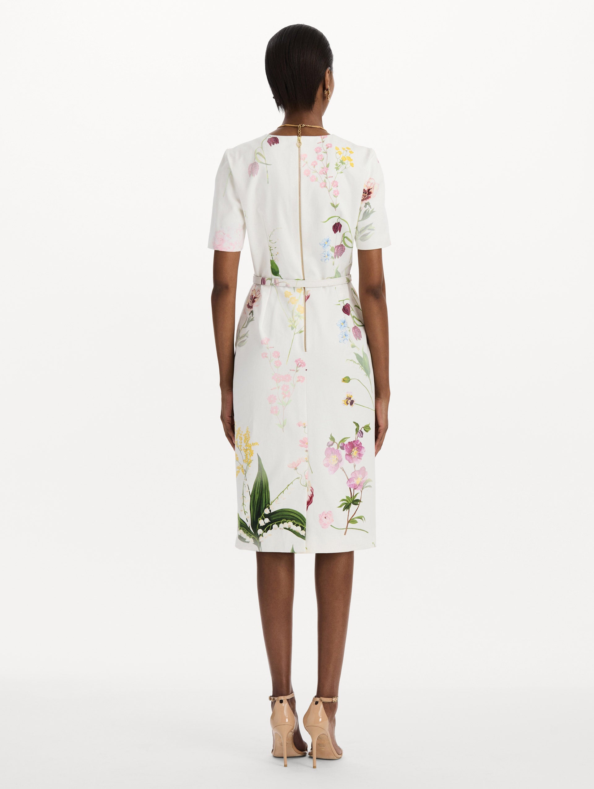 The model is wearing the faded mixed botanical denim dress with midi sleeves and a washed floral print in white multi. Back view.