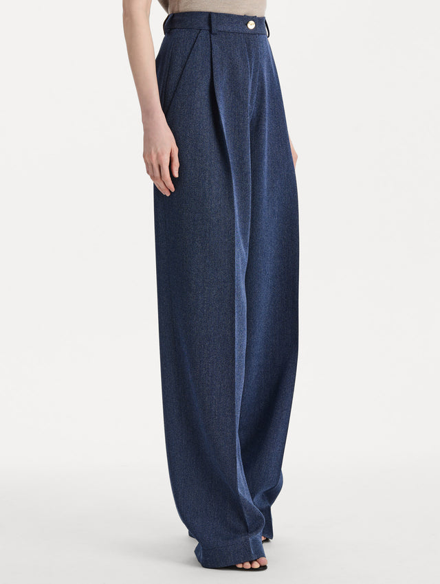 Model wearing indigo wool drill trousers with a straight-leg silhouette. Side view.