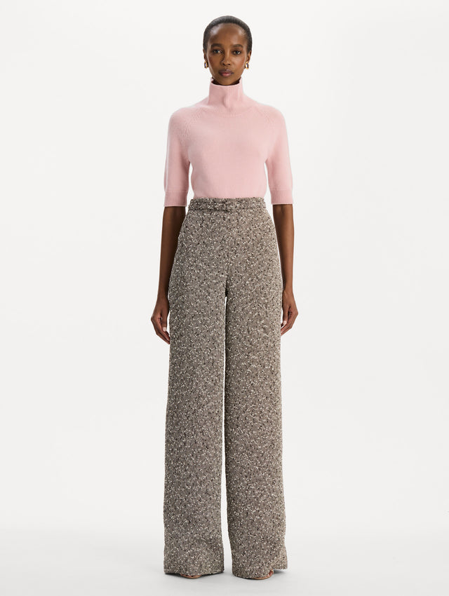 The model is wearing the slubby wool tweed gauze pant with a tailored silhouette in an ivory and brown palette. Front view.