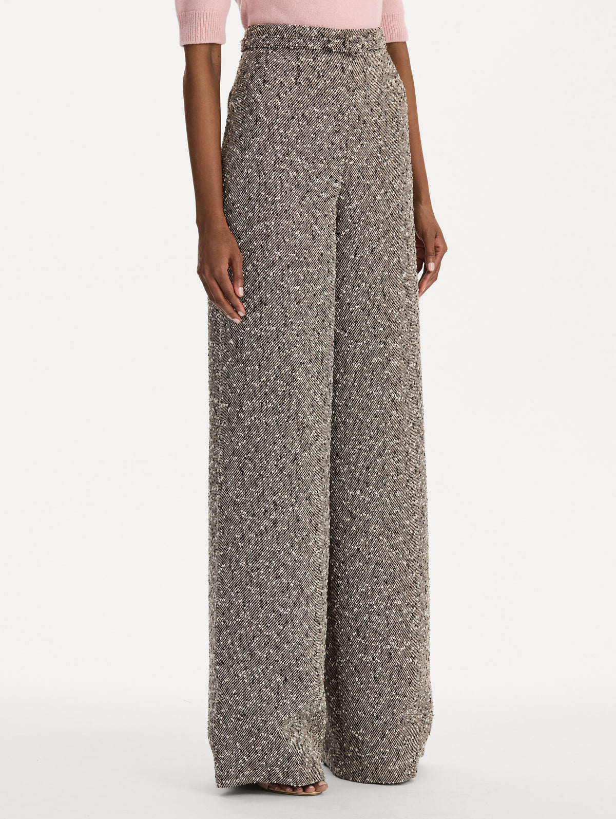 The model is wearing the slubby wool tweed gauze pant with a tailored silhouette in an ivory and brown palette. Side view.