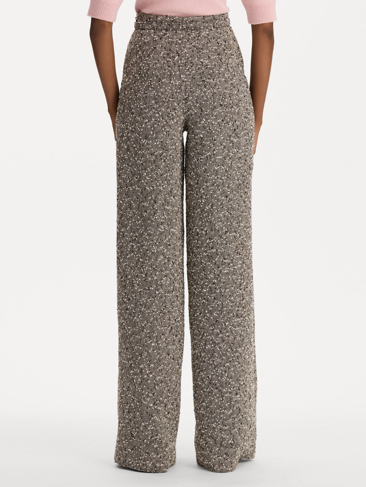 The model is wearing the slubby wool tweed gauze pant with a tailored silhouette in an ivory and brown palette. Back view. 