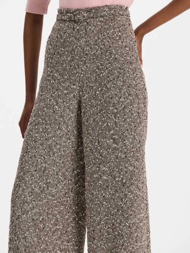 The model is wearing the slubby wool tweed gauze pant with a tailored silhouette in an ivory and brown palette. Zoom view. 