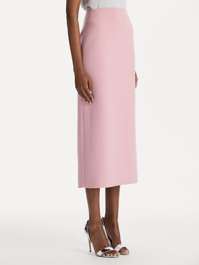 The model is wearing the wool pencil skirt with a structured silhouette in the color blush. Side view. 