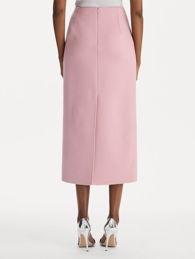 The model is wearing the wool pencil skirt with a structured silhouette in the color blush. Back view. 