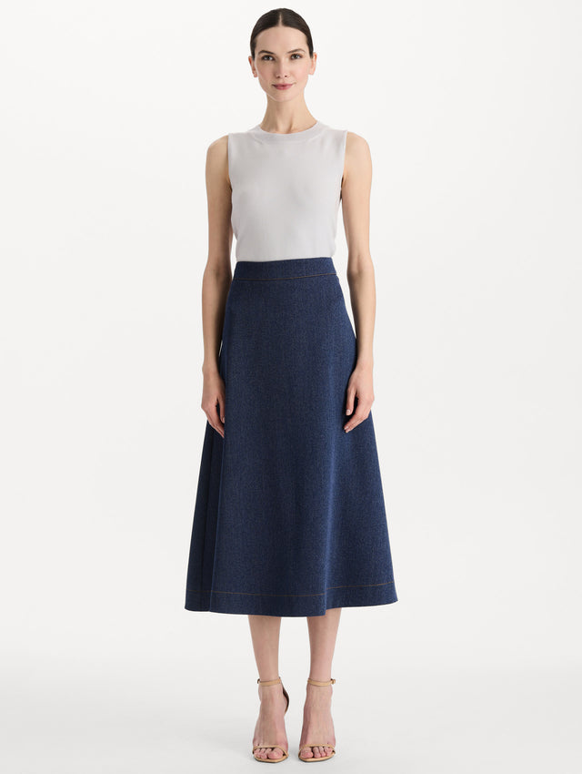 The model is wearing the wool midi skirt in indigo wool with a tailored silhouette. Front view.