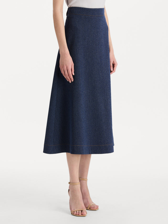 The model is wearing the wool midi skirt in indigo wool with a tailored silhouette. Side view. 