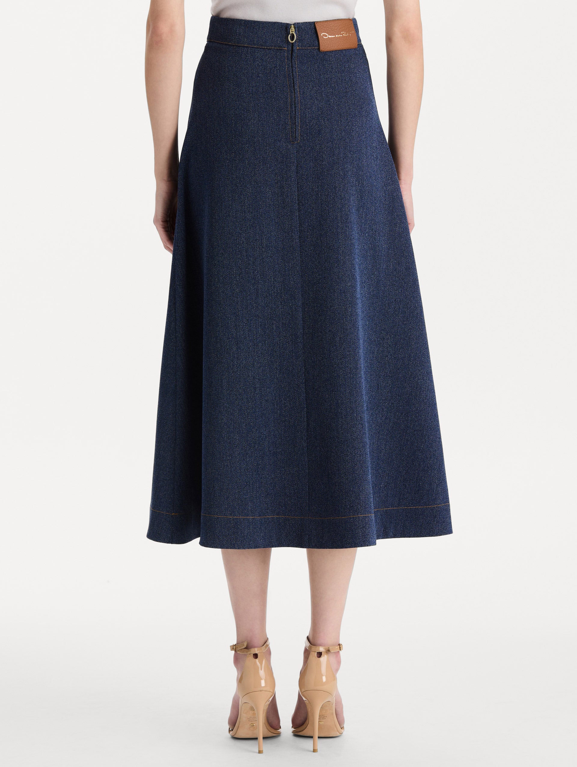 The model is wearing the wool midi skirt in indigo wool with a tailored silhouette. Back view. 