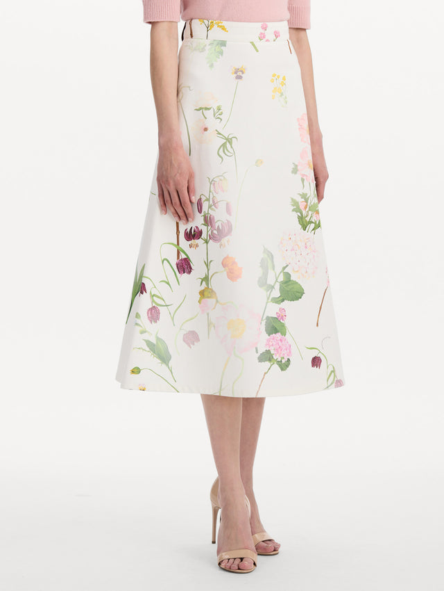 The model is wearing the faded mixed botanical denim midi skirt in the color white multi. Side view.