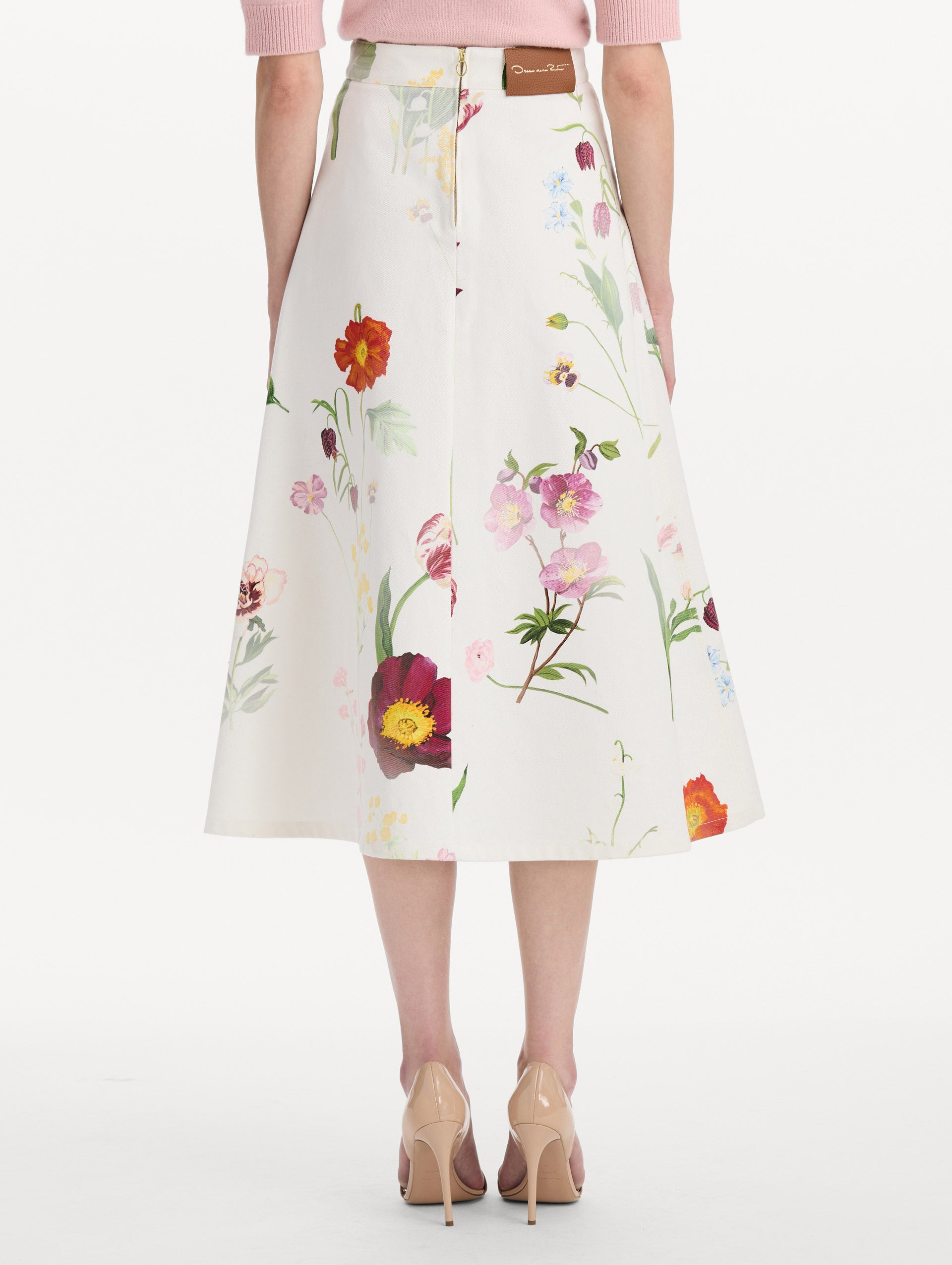 The model is wearing the faded mixed botanical denim midi skirt in the color white multi. Back view.
