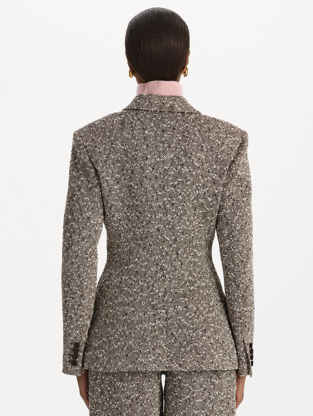 The model is wearing the slub wool tweed collared jacket with long sleeves in an ivory and brown palette. Back view. 