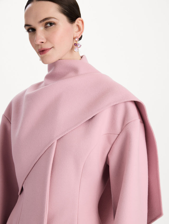 The model is wearing the drape-detailed wool coat with long sleeves in the color blush. Zoom view. 