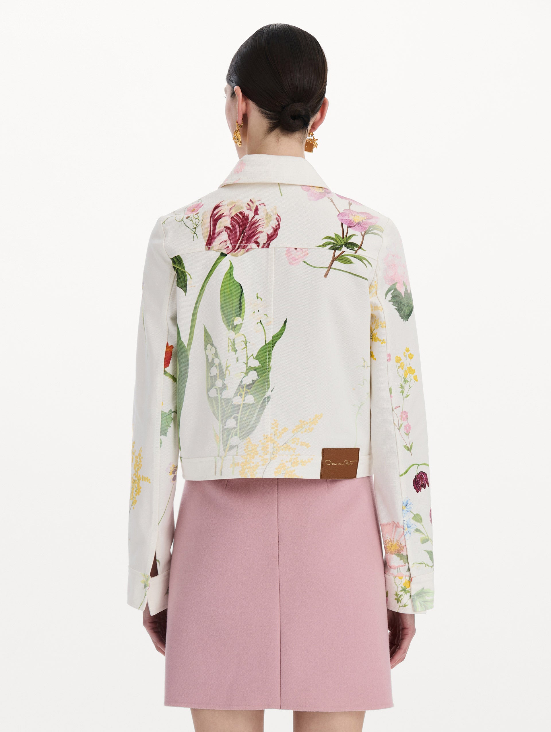 The model is wearing the faded mixed botanical denim jacket in the color white multi. Back view.