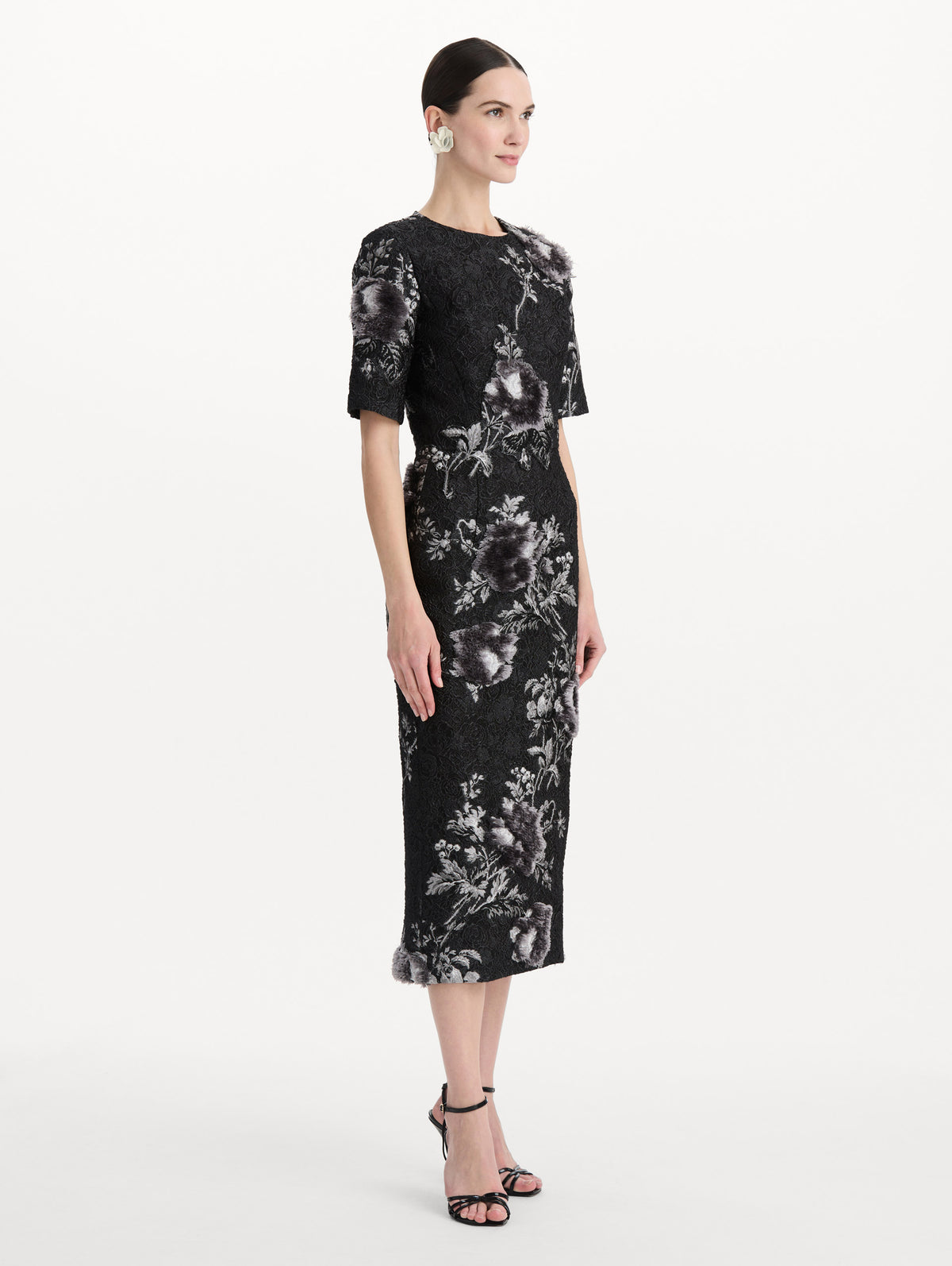 The model is wearing the peony fil coupé cocktail dress with midi sleeves in a white and carbon palette. Side view. 
