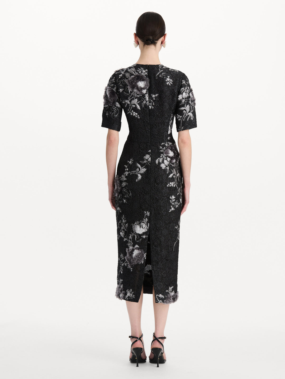 The model is wearing the peony fil coupé cocktail dress with midi sleeves in a white and carbon palette. Back view.