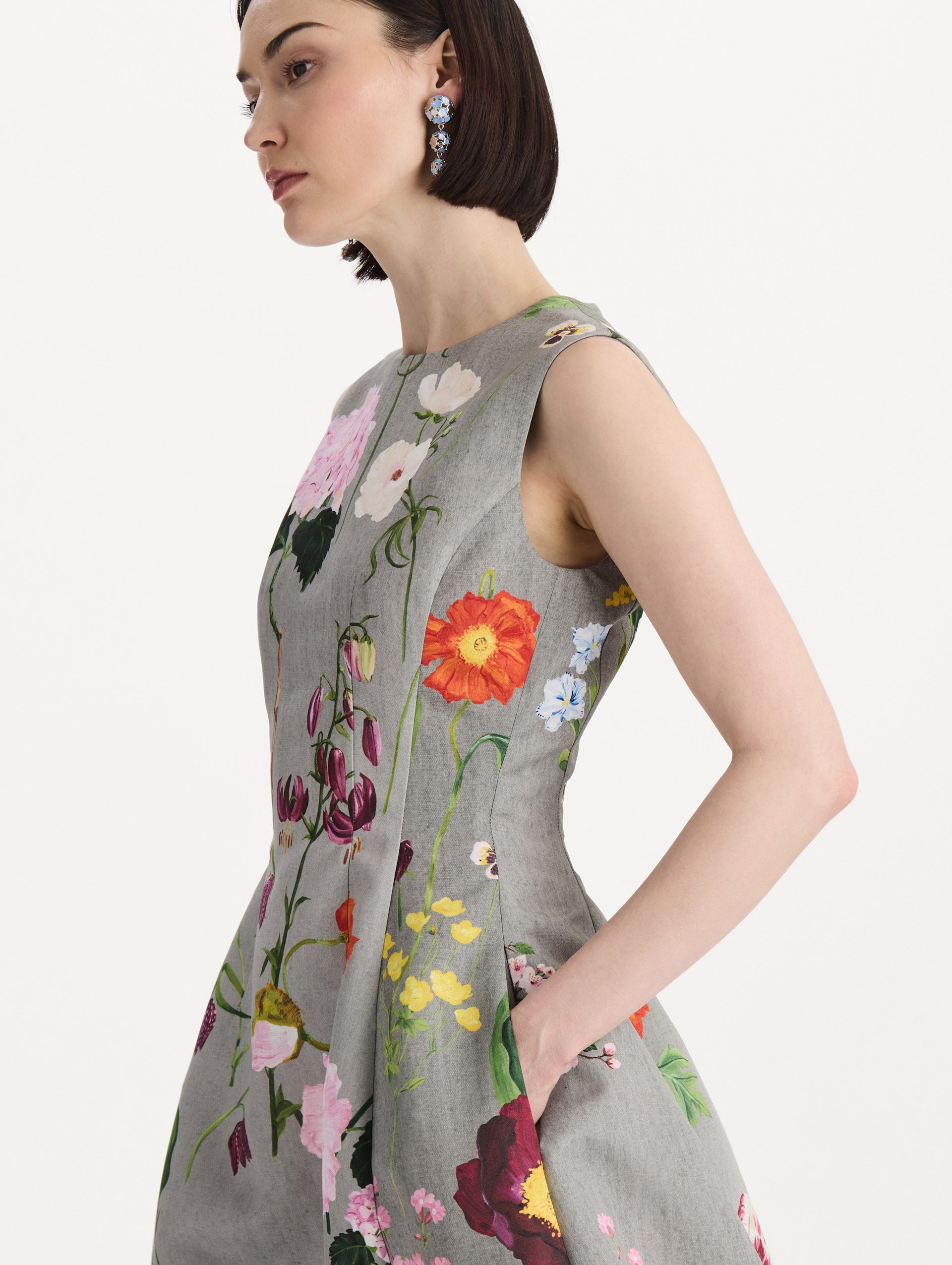 The model is wearing the mixed botanical faille cocktail dress with a sleeveless silhouette in the color grey multi. Zoom view. 