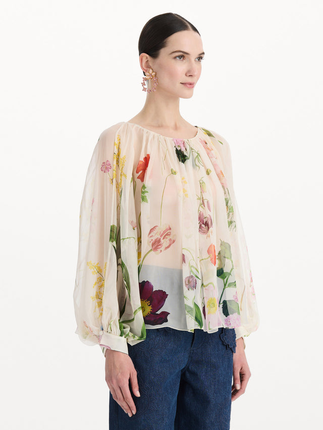The model is wearing the mixed botanical silk chiffon blouse with long sleeves and an all-over floral print in ecru tones. Side view. 
