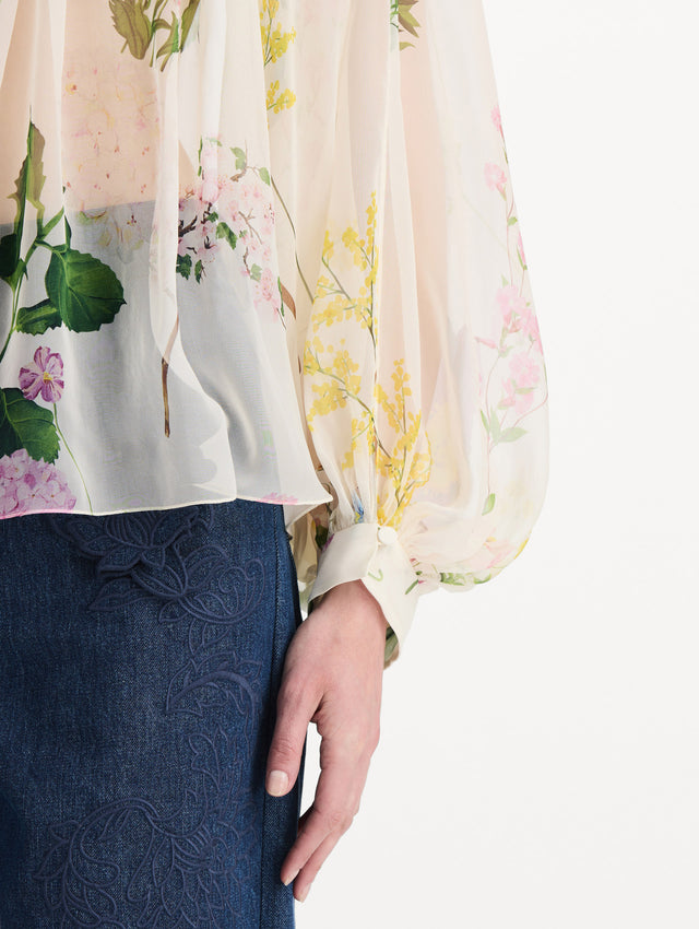 The model is wearing the mixed botanical silk chiffon blouse with long sleeves and an all-over floral print in ecru tones. Zoom view. 