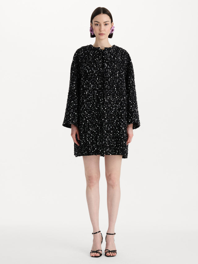 The model is wearing the sequin ribbon tweed coat with a black and white tweed finish and a tailored silhouette. Front view. 