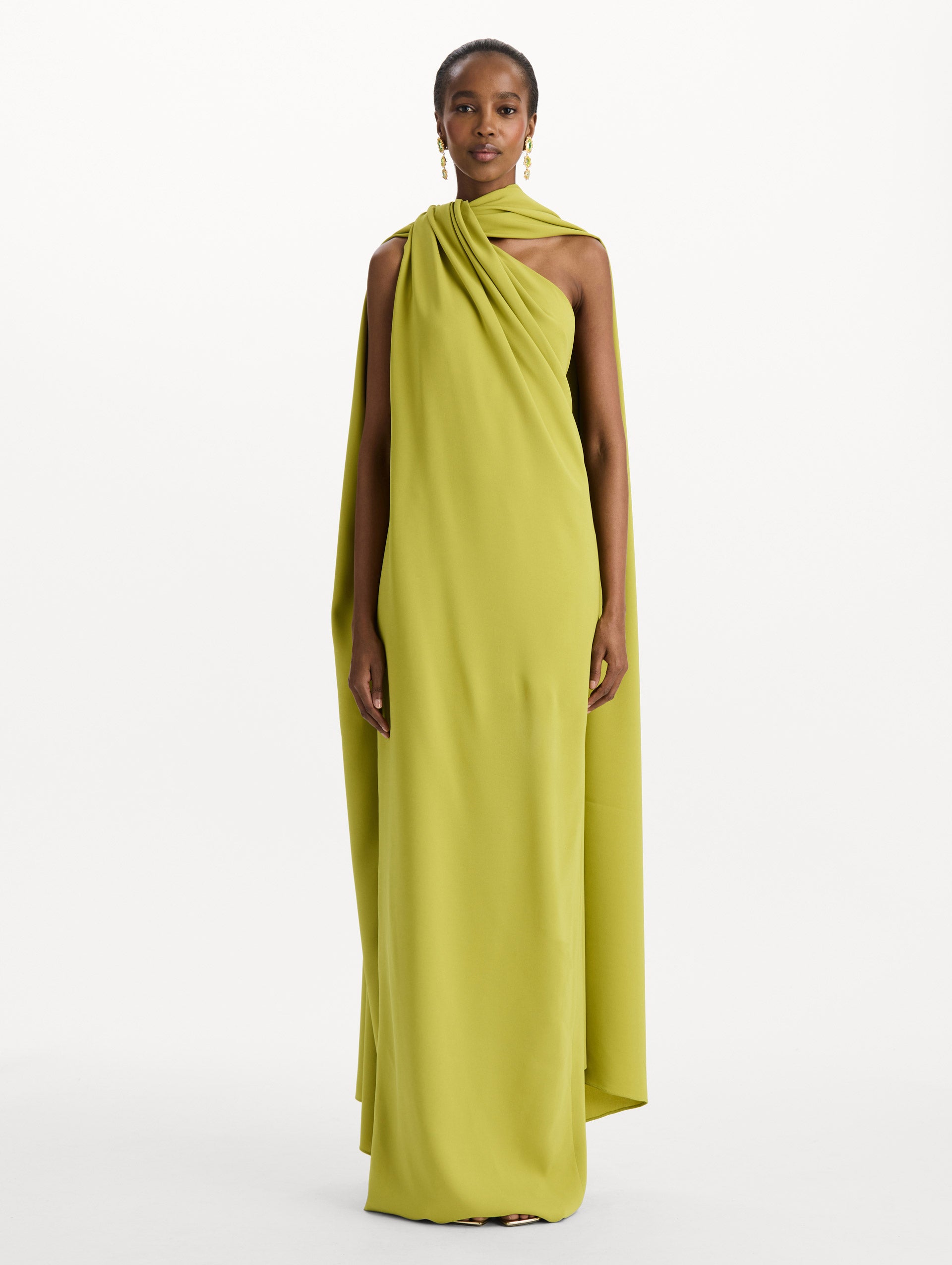 The model is wearing the drape-detailed georgette caftan with a halter neckline in the color peridot. Front view. 