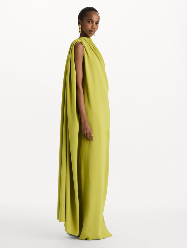 The model is wearing the drape-detailed georgette caftan with a halter neckline in the color peridot. Side view. 