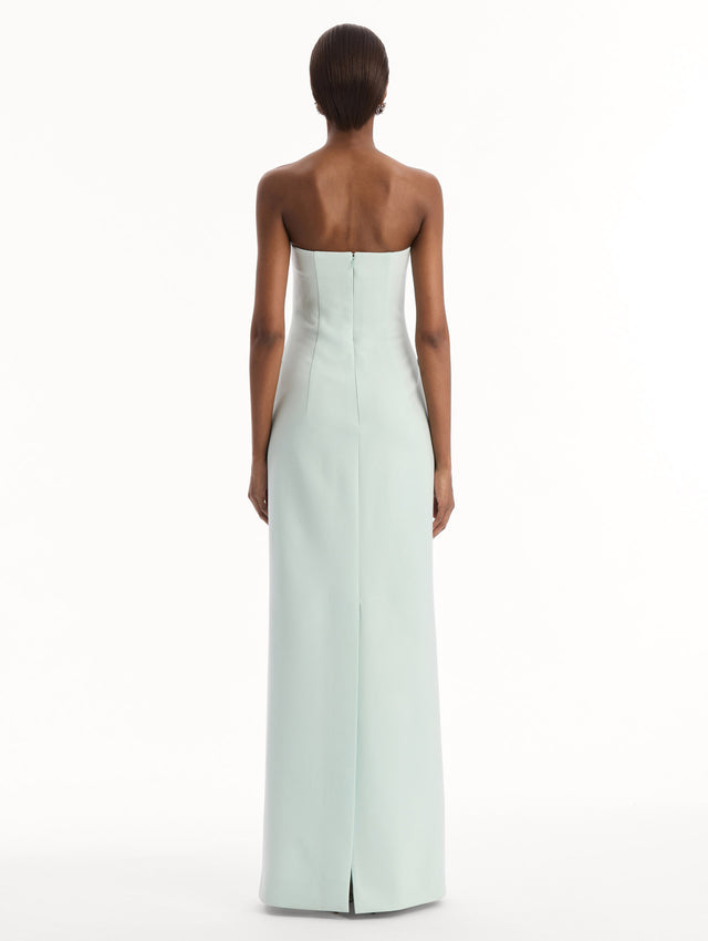 The model is wearing the Crystal Floral Embroidered Gown in Saltwater Blue. Featuring a strapless neckline, faux front flap pockets with crystal embroidery, and a long, column silhouette. Back View.