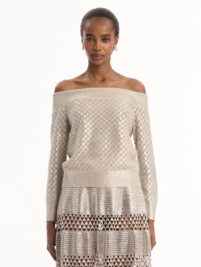 The model is wearing the Silver Foil Off-Shoulder Pullover. Featuring a lattice knit pattern, off-the-shoulder neckline, long sleeves, and ribbed trims. Front View.