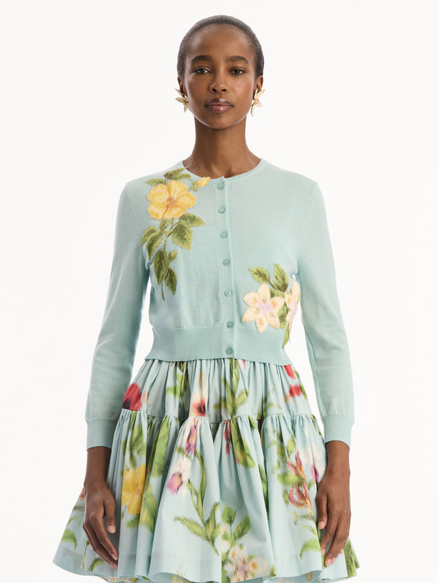 The model is wearing the Chiné Dominican Mixed-Floral Threadwork Cardigan in Saltwater Blue with threaded Dominican florals. Featuring buttons closures down the center, long sleeves, crew neckline, and ribbed trims. Front View.