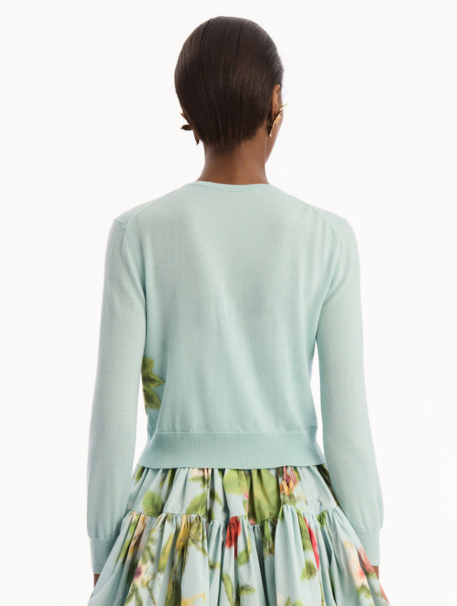 The model is wearing the Chiné Dominican Mixed-Floral Threadwork Cardigan in Saltwater Blue with threaded Dominican florals. Featuring buttons closures down the center, long sleeves, crew neckline, and ribbed trims. Back View.