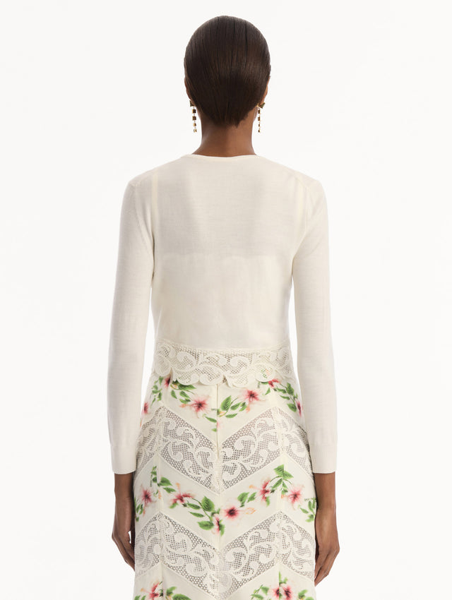 The model is wearing the Chiné Hibiscus Threadwork Cropped Cardigan in Ivory. Featuring a threaded Chiné hibiscus and intricate guipure lace trim. Back View.