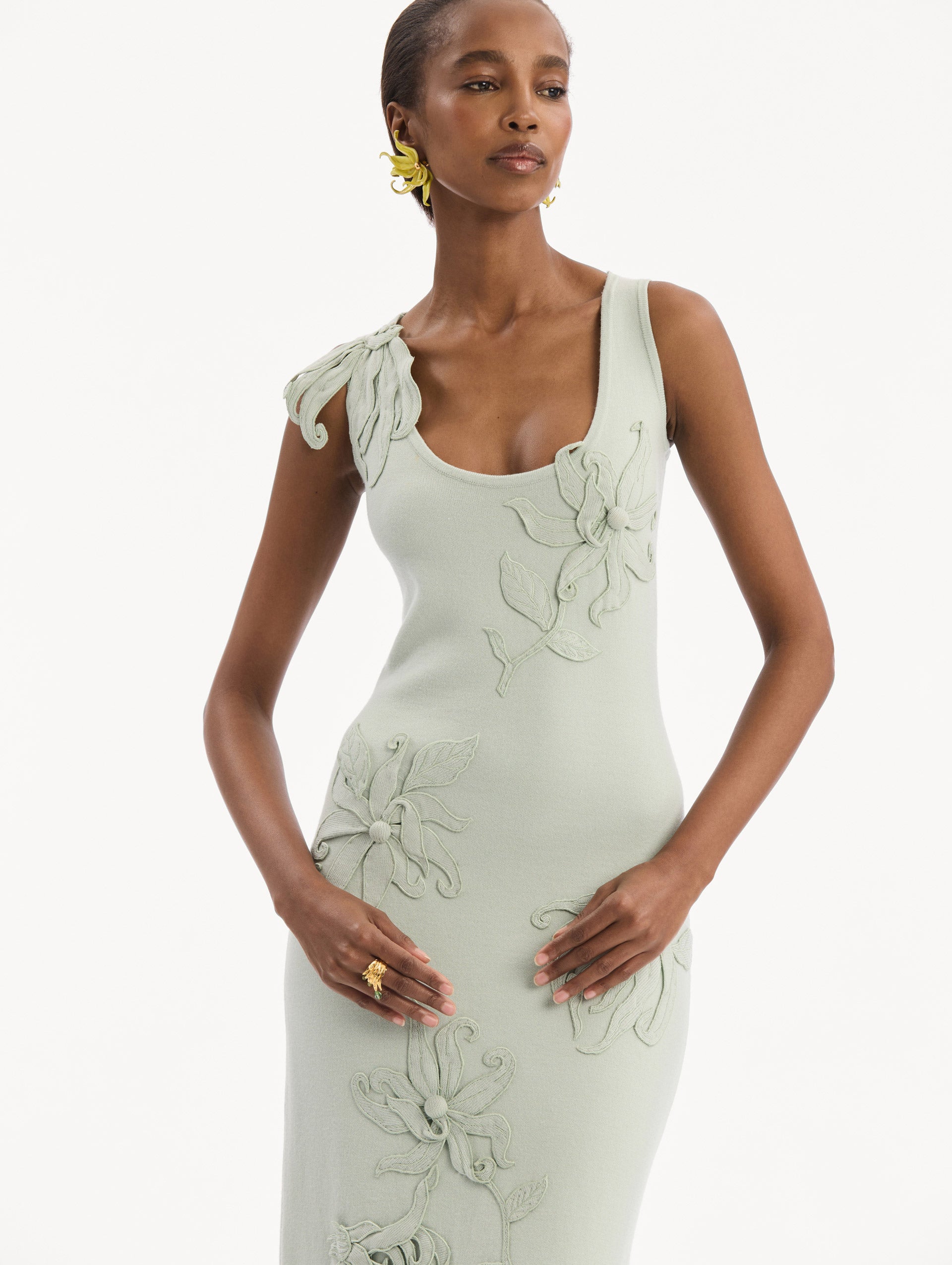 The model is wearing the Hibiscus Embroidered Knit Pencil Dress in Saltwater Blue. Featuring a structural hibiscus embroidery, a scoop neckline, and midi length. Detail View.